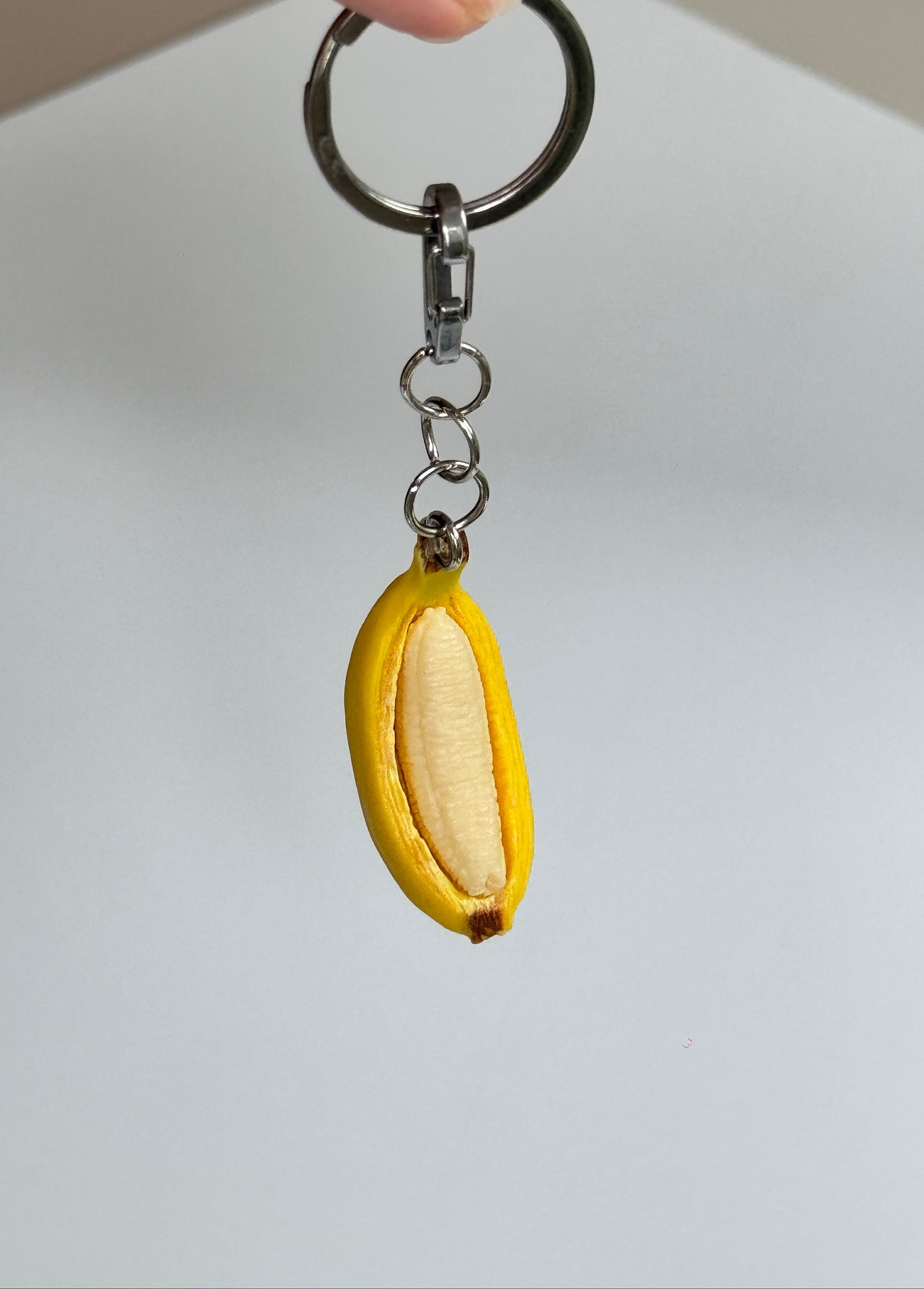 Keychain shaped like a banana with a white center on a plain background
