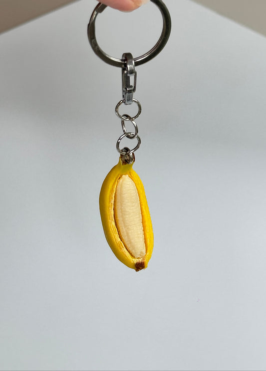 Keychain shaped like a banana with a white center on a plain background
